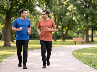 Obraz premium Two senior Indian male friends laughing during a morning jog in a green park for healthy aging fitness wellness longevity retirement and healthcare advertising