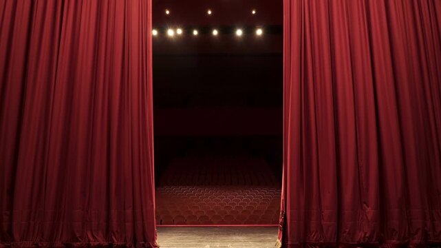 Theatre stage with parted red curtains, empty concert hall seats and overhead stage lighting