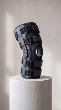 Abstract sculpture resembling a twisted form made of textured dark material on a cylindrical pedestal against a neutral backdrop