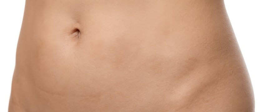Close up of a toned abdomen with a navel on a plain background