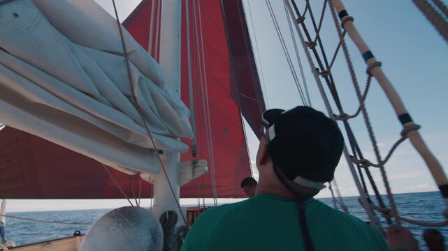 Person works on the big sailing boat moving in the Atlantic Ocean under the sails