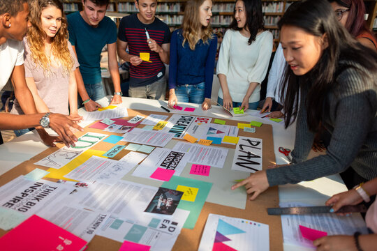 Diverse group collaborating on a creative project with notes and papers.