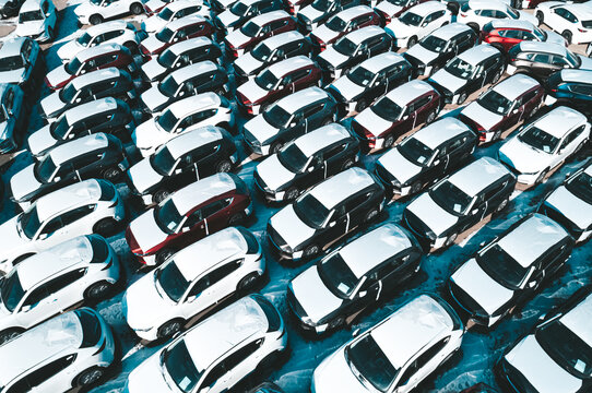 Aerial view of new cars parked in car parking lot. Car dealer parking lot full of new automobiles. New cars lined up for import and export business.