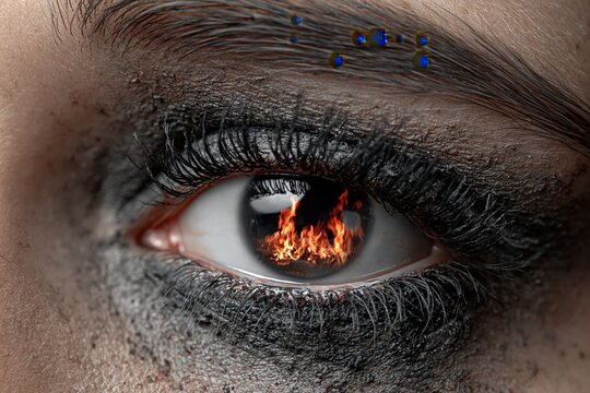 Female eye with fire reflection and dramatic dark makeup close up