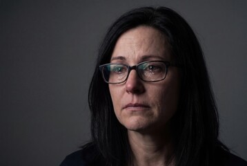 Fototapeta premium Depressed middle aged woman crying with glasses emotional portrait