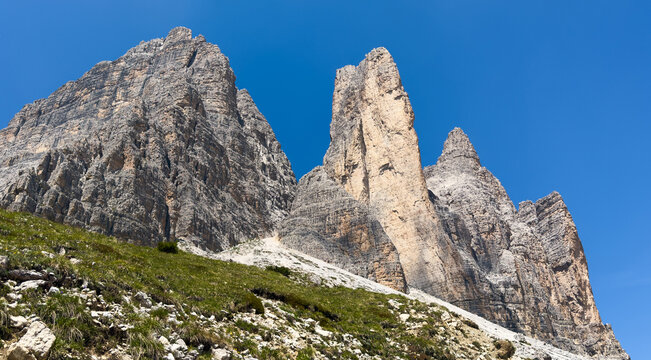 panorama of Tre Cime in the Dolomites, highlighting jagged cliffs and green meadows 