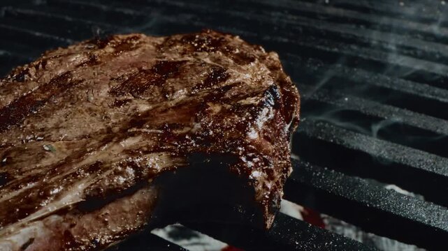 Close up of juicy steak sizzling on a grill with charred marks and smoky juices