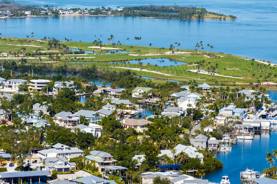 Wealthy neighborhood in small town Boca Grande, Florida with expensive waterfront houses between green palm trees. Development of US premium housing
