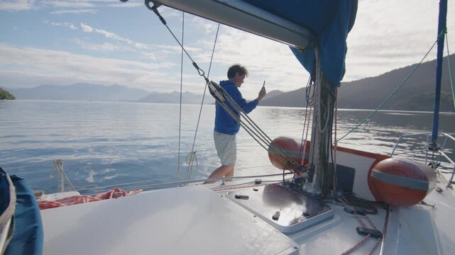 Young man enjoys the morning time on the sailing boat anchored in the calm bay