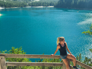 Obraz premium Hiking, excited and woman on mountain with lake for adventure, trekking and freedom. Travel, nature and happy person outdoors for wellness, walking and exercise on holiday, journey and vacation