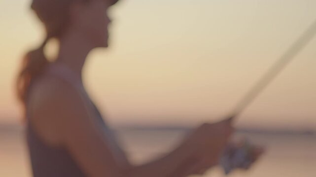 Young woman fishing on the river during sunset