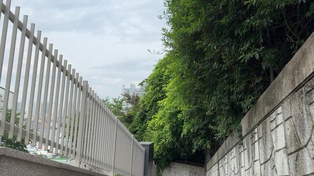Modern metal fence and stone retaining wall with lush green trees