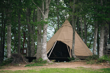 Tent campsite forest tree canvas teepee woodland shelter outdoor Canvas teepee tent quiet forest campsite among tall tree trunk, grass path, wooden sign, natural woodland shelter, peaceful outdoor © chokniti