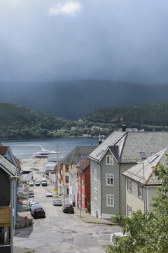 Norwegian Coastal Street View in Alesund. Traditional scandinavian coastal houses with ocean bay, mountains under dramatic sky, Norway.