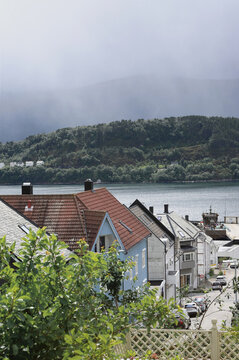 Norwegian Coastal Street View in Alesund. Traditional scandinavian coastal houses with ocean bay, mountains under dramatic sky, Norway.