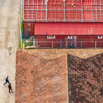 Belgrade, Serbia - 15 November 2025: Aerial view of red-tiled rooftops and industrial buildings near the FK GSP Polet Dorcol football grounds, with two people walking on a path.