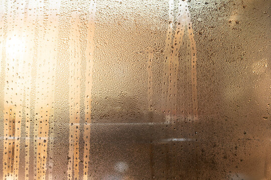 Condensation glass window droplet moisture texture abstract condensation covered glass window with water droplet texture and warm light creating private, atmospheric surface for background design