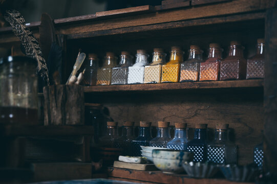 Rustic wooden shelf with decorative glass bottle collection and colorful spice jar, evoking mysterious vintage apothecary atmosphere