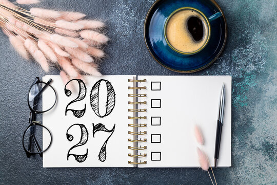 New year resolutions 2027 on desk. 2027 goals list with notebook, coffee cup, plant on table. Resolutions, plan, goals, action, checklist, idea concept. New Year 2027 resolutions, copy space