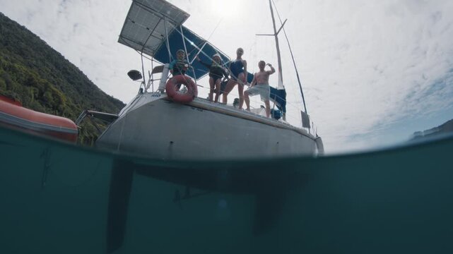 Splitted underwater view of the sailing boat with family with kids on it
