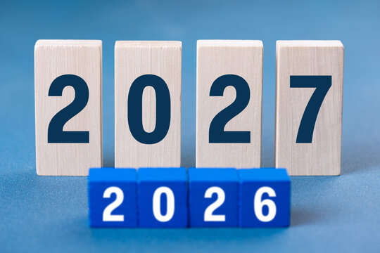 2027 Happy New Year. Wooden cube block change from 2026 to 2027 on blue. Concept 2027 New Year background. Business, resolutions, goals, inspiration, success, ideas