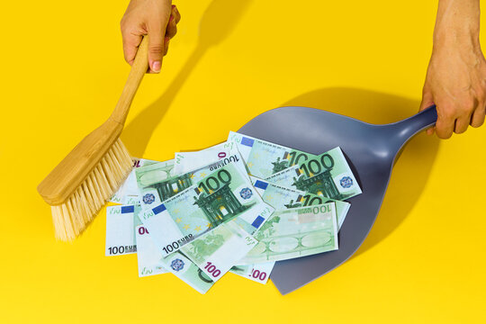 Hands sweeping hundred dollar bills with broom