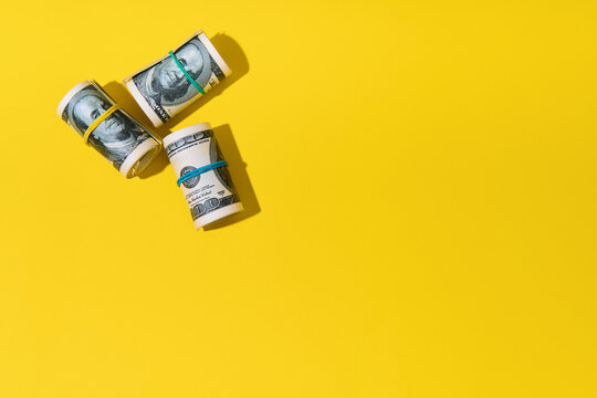  Rolls of hundred dollar bills on yellow background