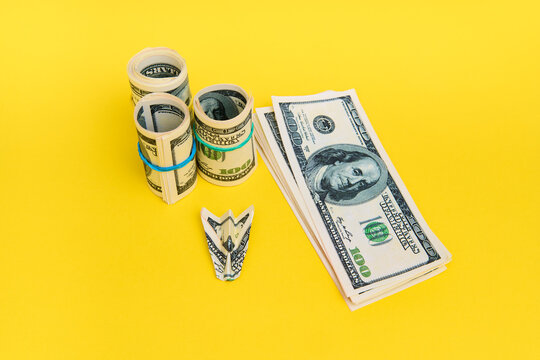 Money airplane with hundred dollar bills on yellow background