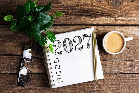 New year resolutions 2027 on desk. 2027 goals list with notebook, coffee cup, plant on wooden table. Resolutions, plan, goals, action, checklist, idea concept. New Year 2027 resolutions, copy space