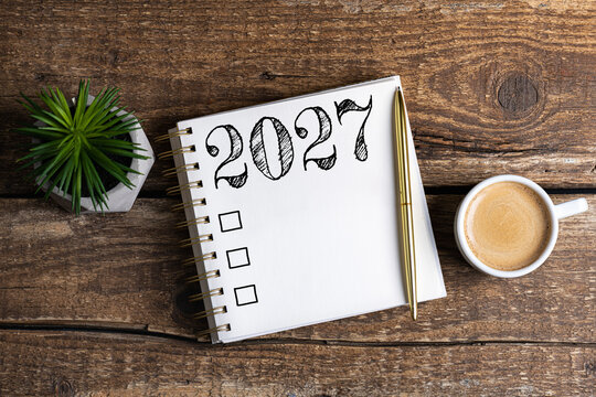 New year resolutions 2027 on desk. 2027 goals list with notebook, coffee cup, plant on wooden table. Resolutions, plan, goals, action, checklist, idea concept. New Year 2027 resolutions, copy space