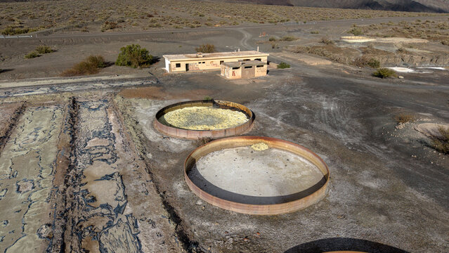 Calingasta, San Juan, Argentina - 16 July 2026: Aerial view of Ruinas de Planta de Sulfato de Aluminio featuring large circular industrial tanks and abandoned buildings in a desert landscape.