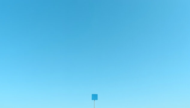 Minimalist photography of a tiny blue sign lost in a vast and empty clear blue sky background