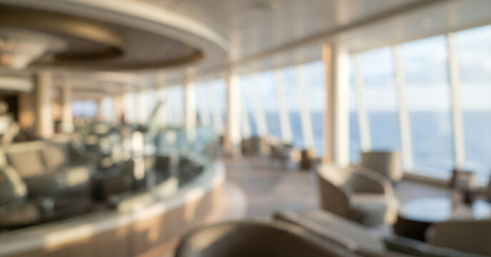 Expansive cruise ship upper deck interior fully blurred with panoramic glass structures, comfortable lounge areas and soft daylight for luxury travel tourism and vacation backgrounds