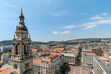 Naklejka premium Wide view of a bell tower and clock overlooking the streets and rooftops of Budapest from Saint Stephen's Basilica