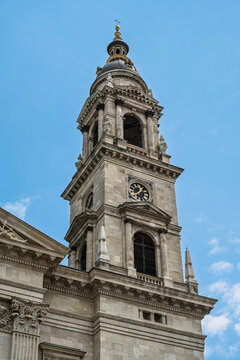 Upward view of the clock tower topped by a small dome and gilded cross on Saint Stephen's Basilica in Budapest
