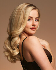 Closeup profile portrait of a sensual smile blonde model with make-up and hairstyle, holding a hands near neck, posing in studio, isolated on a dark pink background. © Corina