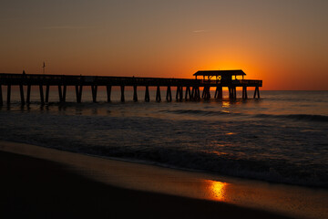 Fototapeta premium Tybee Island ocean fishing pier silhouette at golden sunrise, Georgia, USA.