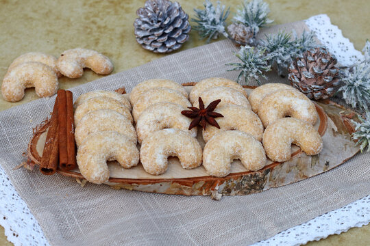 Traditionelle Vanillekipferl auf einer Baumscheibe mit Zimtstangen,Sternanis und weihnachtlicher Dekoration.