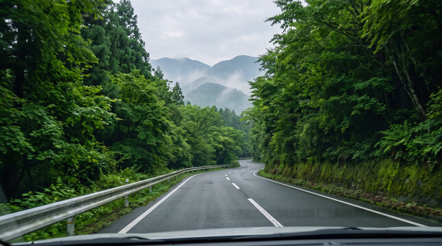 Scenic road winding through lush green forests with layered mountains in the distance, representing peaceful travel through Japan.