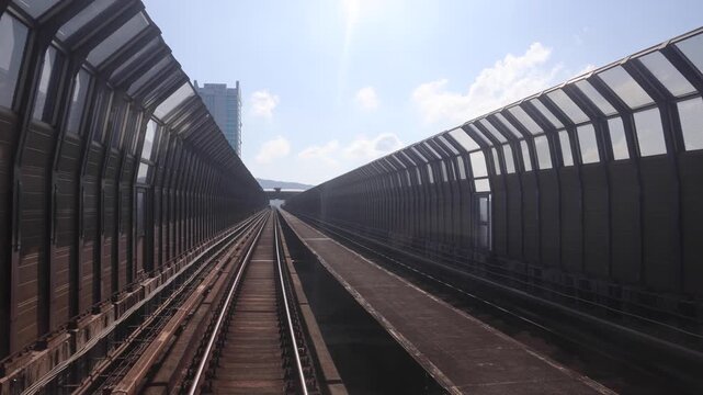 Perspective view of mass rail transit train passing through tracks with sound barrier in the city of Kuala Lumpur. Sound barrier tunnels are designed to minimize noise pollution.