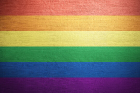 Rainbow pride flag painted on flat wooden surface featuring six vibrant horizontal color stripes natural wood grain texture colorful background celebrating diversity equality inclusion and identity