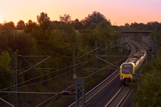 Intercity train traveling through a scenic railway corridor at sunset, surrounded by trees and overhead power lines. Stuttgart to Mannheim, Baden-W&uuml;rttemberg, Germany
