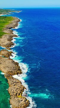 Atlantic coastline with surf at Mar Chiquita, Manati, Puerto Rico. Overhead shot of breaking waves crashing against rugged volcanic rocks and shallow reef. Vertical video.