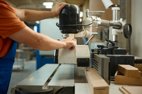 Skilled technician precisely guides cutting tool to produce detailed and flawless wood contours