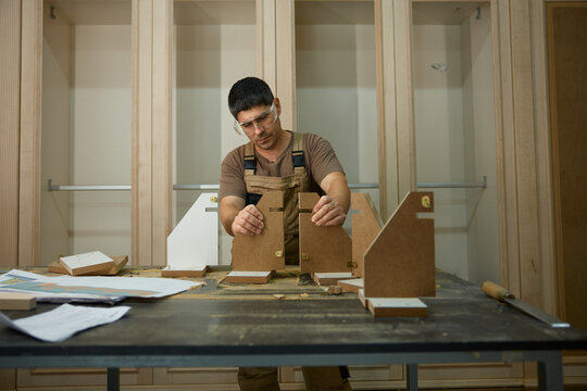 Diligent worker carefully positioning and measuring components for personalized furniture creation