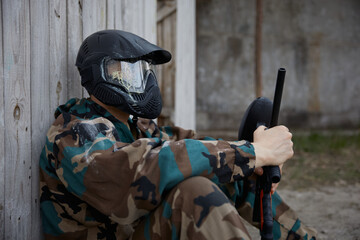 Fototapeta premium An individual soldier is sitting down on the ground, holding a weapon at the battlefield