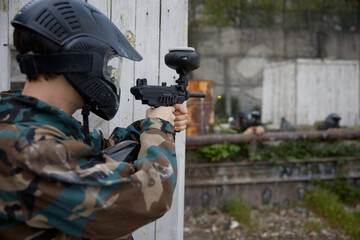 Fototapeta premium Paintball soldier is taking a defensive position behind the cover during tactical weapon training