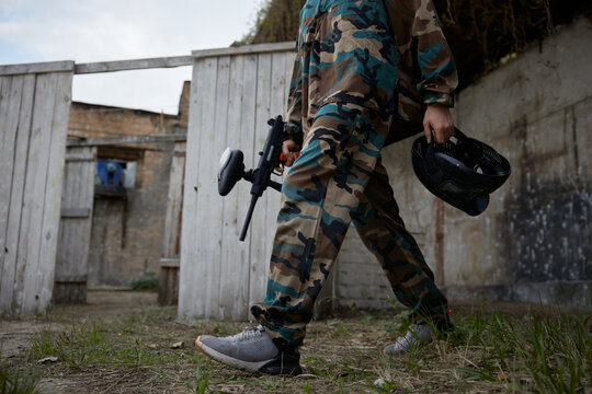 Soldier is walking through the training field, holding a weapon and a helmet