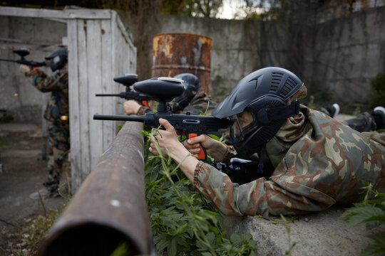 Portrait of a soldier aims a gun while leaning on a pipe, lying on the ground