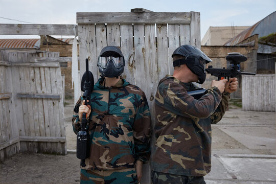 Armed group of several people practice with paintball weapons on a training field outdoor